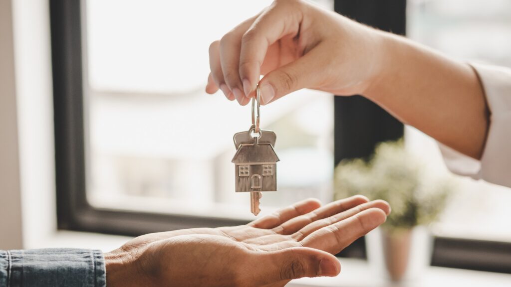 Nahaufnahme der Hand eines Immobilienmaklers, der die Schlüssel an einen Mieter übergibt