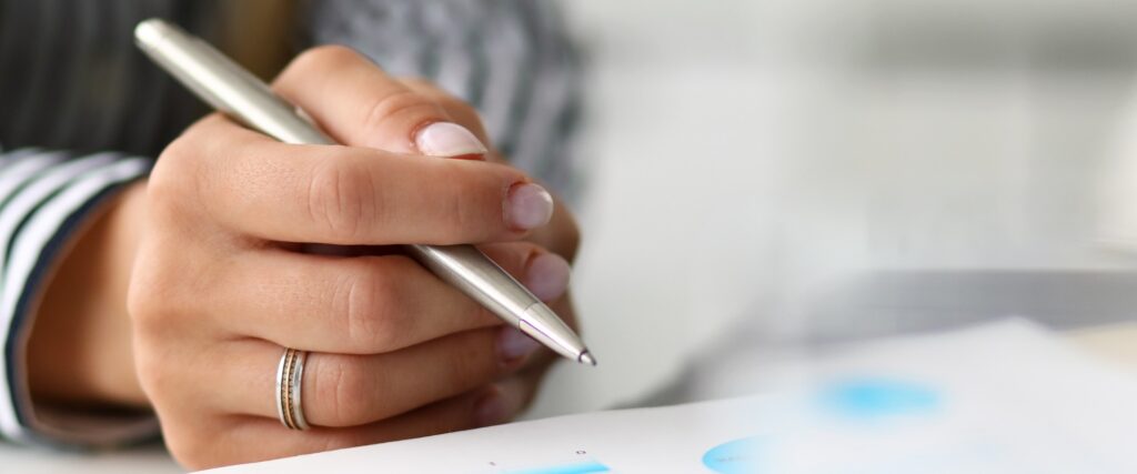 Eine Frau mit Kugelschreiber in der Hand bei der Steuererklärung